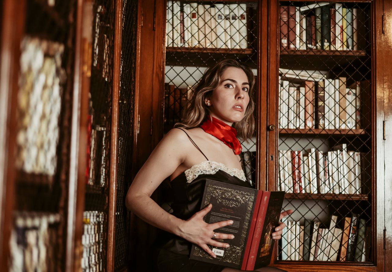Mastering the First Impression: Your intriguing post title goes here Elegant woman holding a book in a classic library, evoking a vintage atmosphere.